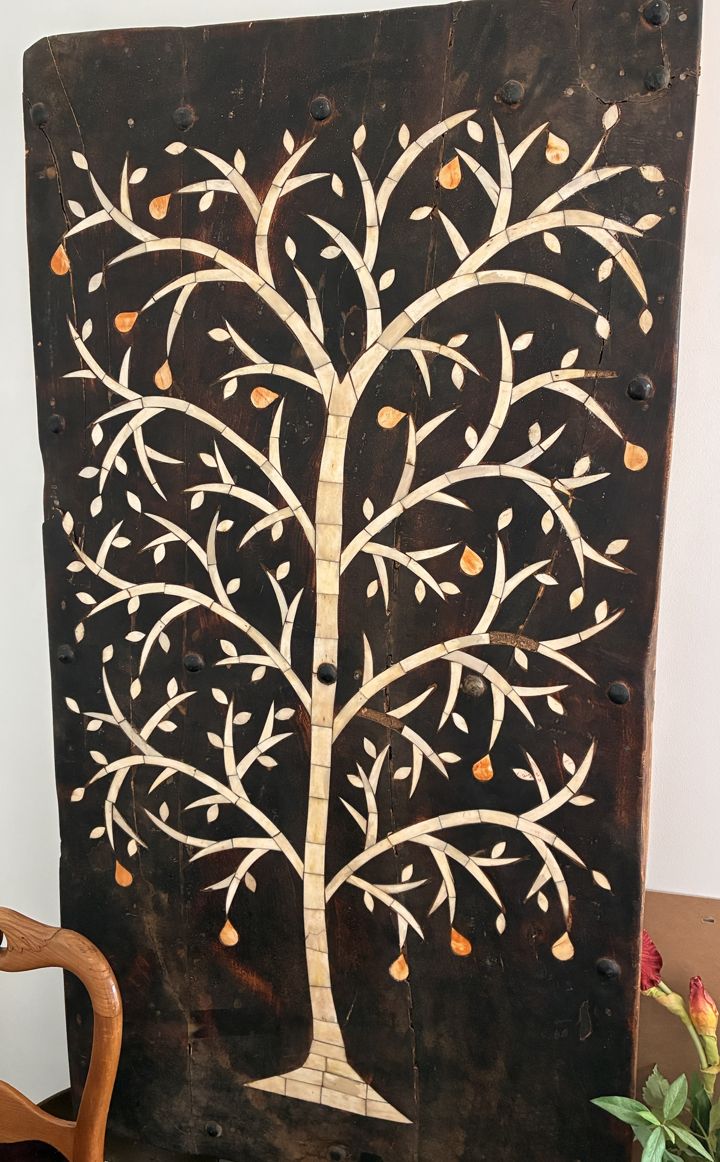 Porte berbère en bois sombre incrustée d'un arbre de vie aux branches claires et aux fruits orangés, pièce maîtresse du cabinet